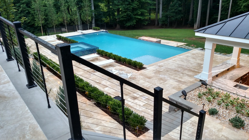 Ejemplo de casa de la piscina y piscina infinita minimalista extra grande rectangular en patio trasero con adoquines de piedra natural