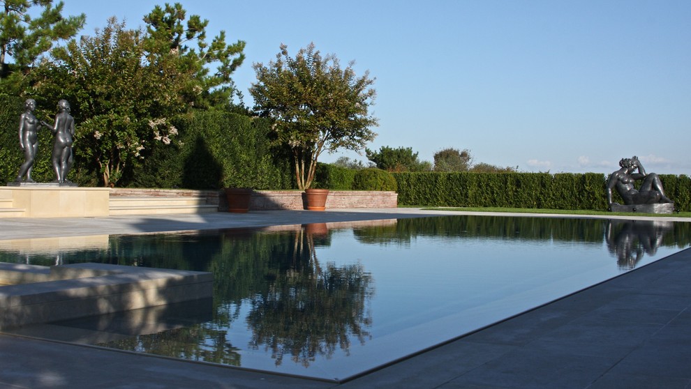 Diseño de piscinas y jacuzzis infinitos actuales grandes rectangulares en patio trasero con adoquines de piedra natural