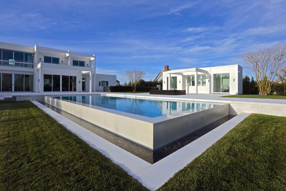 Diseño de casa de la piscina y piscina infinita minimalista rectangular en patio trasero con adoquines de hormigón