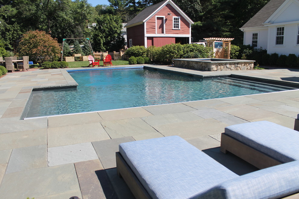 Idée de décoration pour une grande piscine naturelle et arrière champêtre sur mesure avec un bain bouillonnant et du béton estampé.