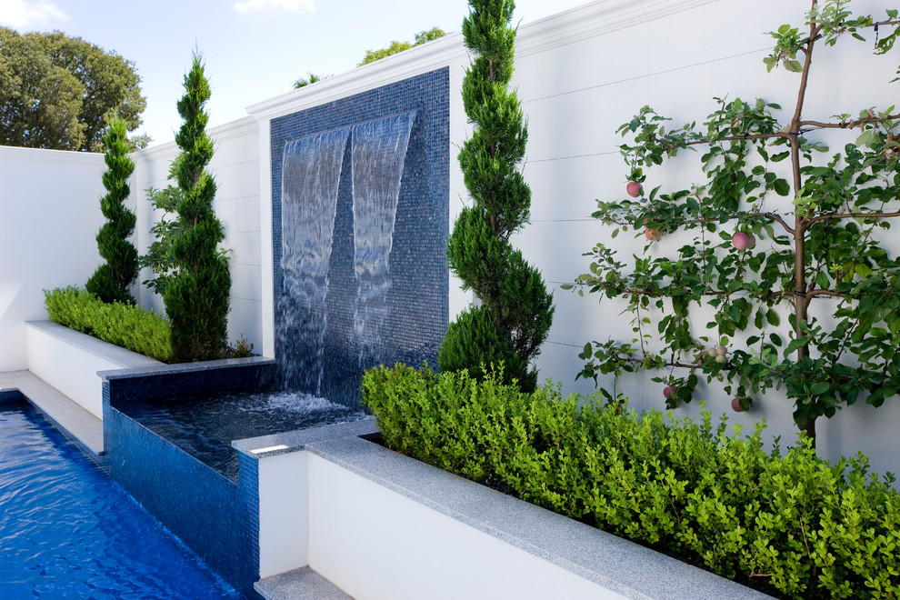 Foto på en mellanstor funkis baddamm på baksidan av huset, med en fontän och naturstensplattor