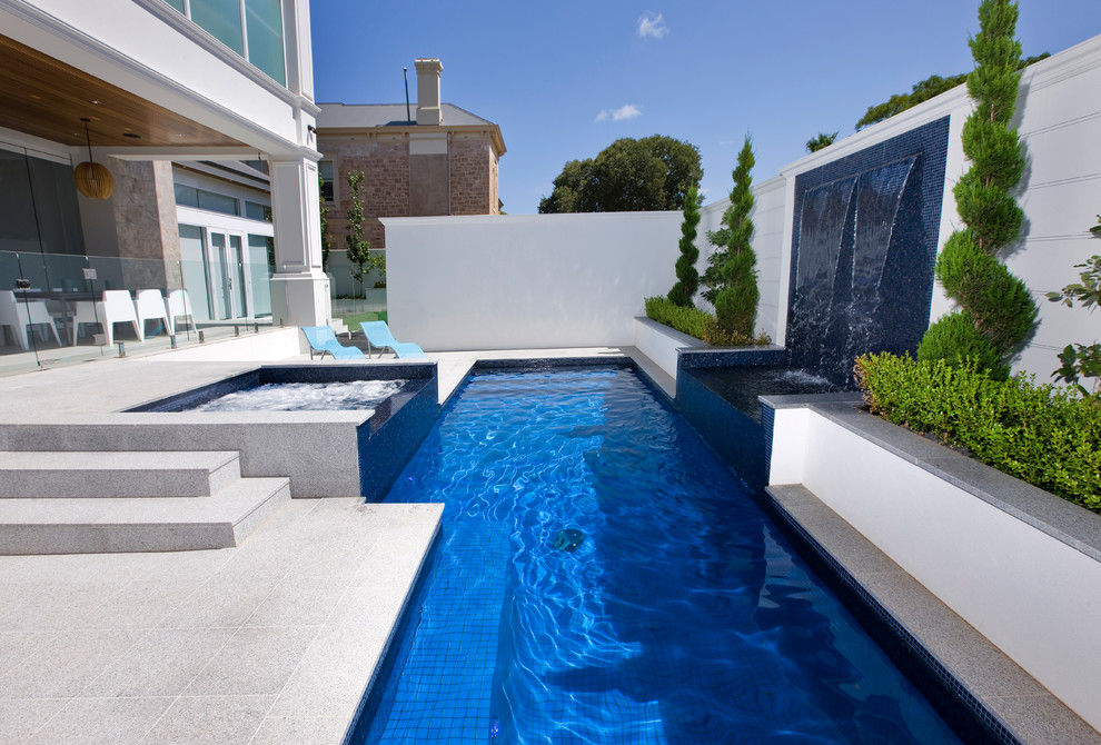 Aménagement d'une piscine naturelle et arrière contemporaine de taille moyenne et rectangle avec un point d'eau et des pavés en pierre naturelle.