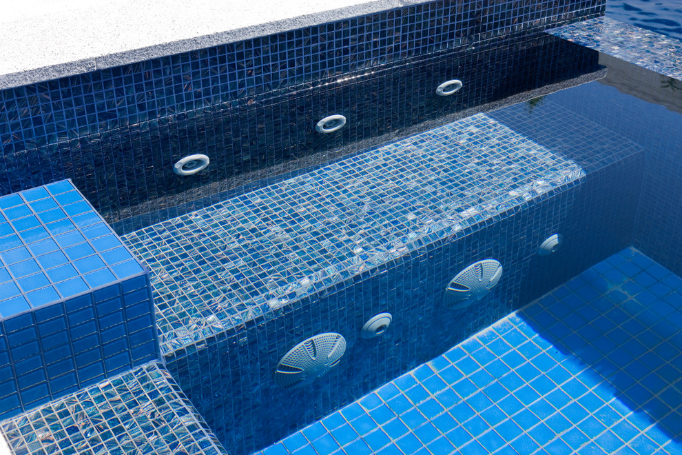 Foto di una piscina naturale design rettangolare di medie dimensioni e dietro casa con fontane e pavimentazioni in pietra naturale