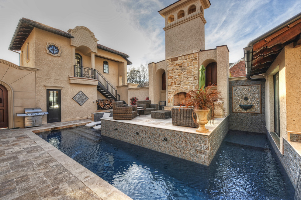 Immagine di una piccola piscina mediterranea personalizzata in cortile con una vasca idromassaggio e pavimentazioni in pietra naturale