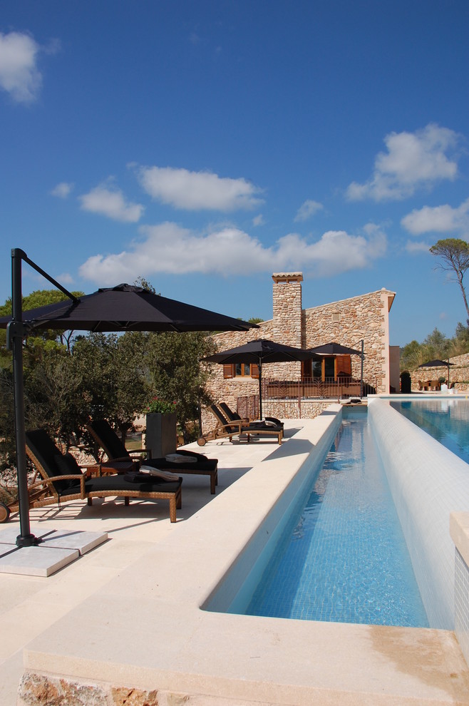 Ejemplo de piscina elevada mediterránea grande en patio lateral con adoquines de hormigón