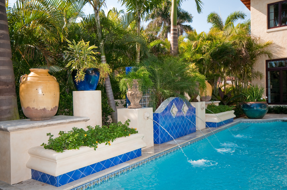 Example of a large tuscan backyard custom-shaped and tile lap pool fountain design in Miami