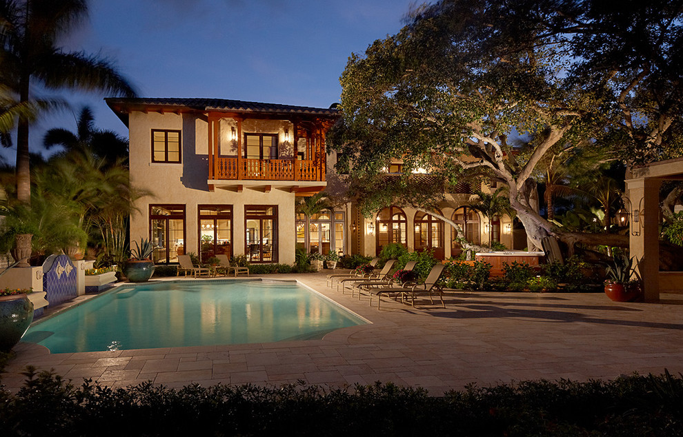 Photo of a large mediterranean back custom shaped lengths swimming pool in Miami with a water feature and tiled flooring.