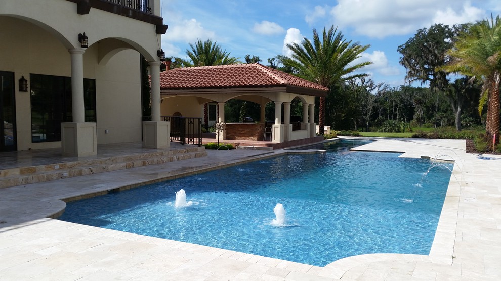 Immagine di un'ampia piscina mediterranea personalizzata dietro casa con fontane e piastrelle