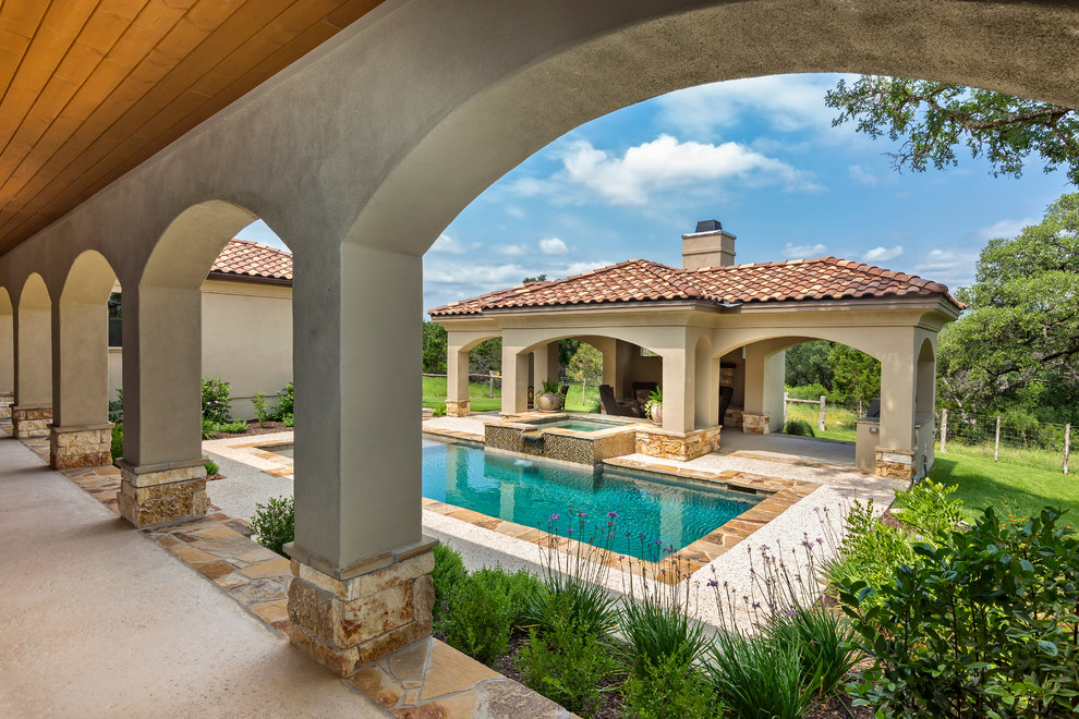 Пример оригинального дизайна: большой прямоугольный бассейн на заднем дворе в средиземноморском стиле с покрытием из каменной брусчатки и джакузи