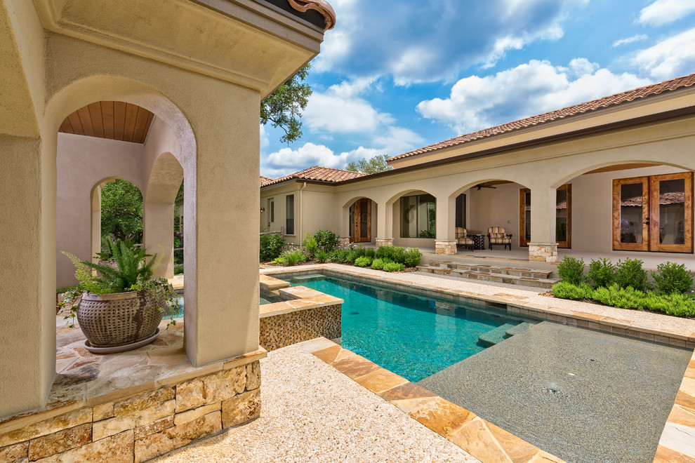 Imagen de piscina con fuente alargada mediterránea grande rectangular en patio trasero con adoquines de piedra natural