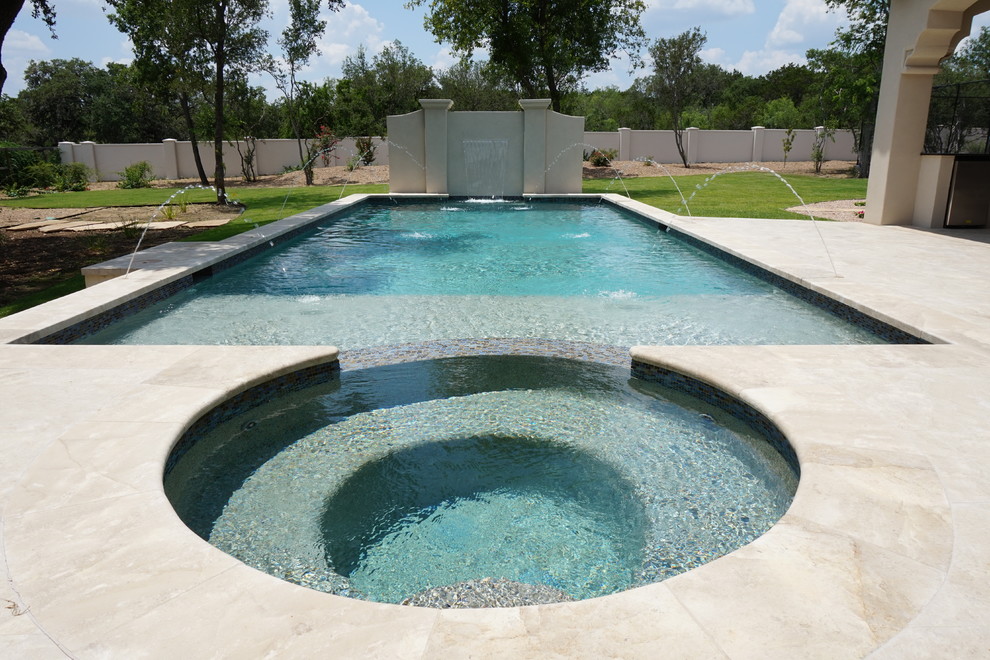Modelo de piscina con fuente alargada mediterránea grande rectangular en patio trasero con suelo de hormigón estampado