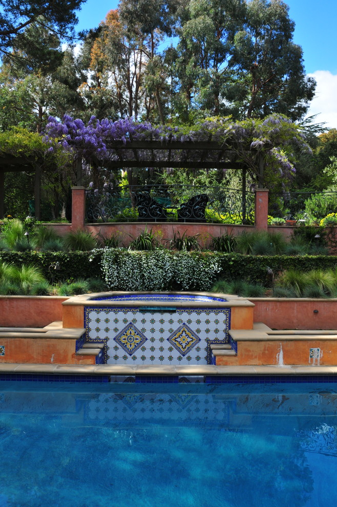 Esempio di una grande piscina mediterranea rettangolare dietro casa con fontane e cemento stampato