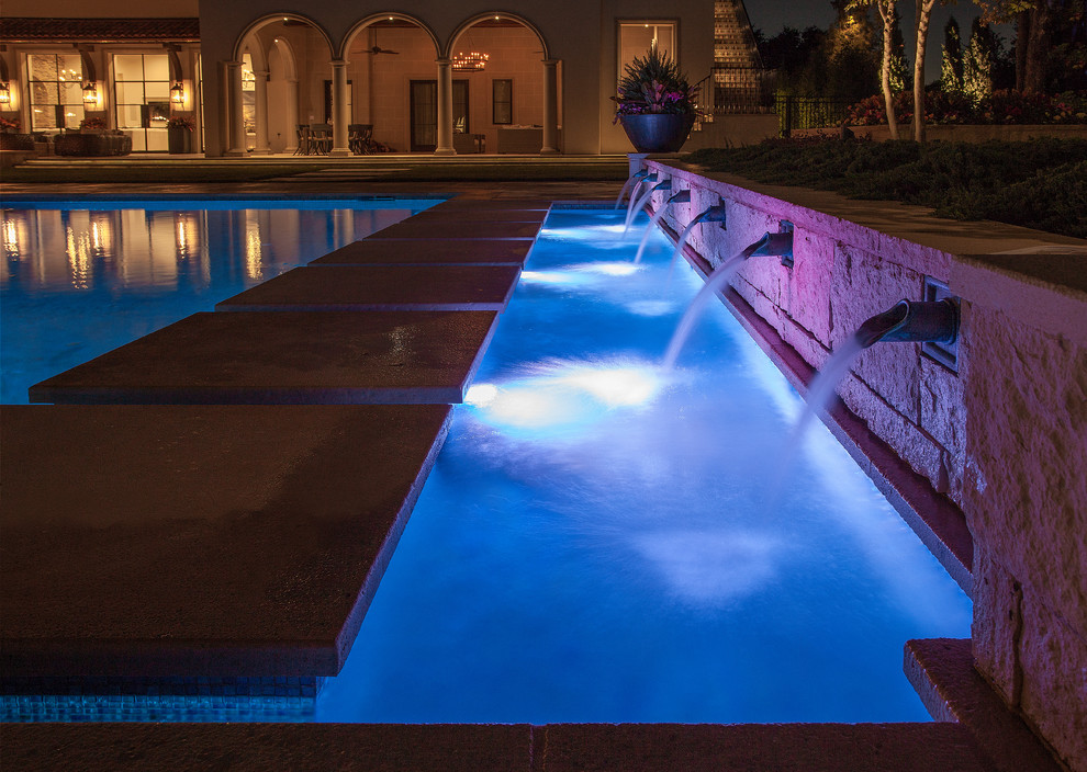 Idee per un'ampia piscina mediterranea rettangolare dietro casa con fontane e pavimentazioni in pietra naturale