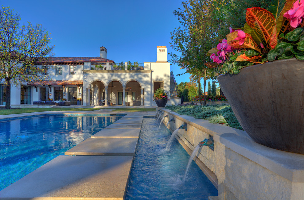 Idee per un'ampia piscina monocorsia mediterranea rettangolare dietro casa con fontane e pavimentazioni in pietra naturale