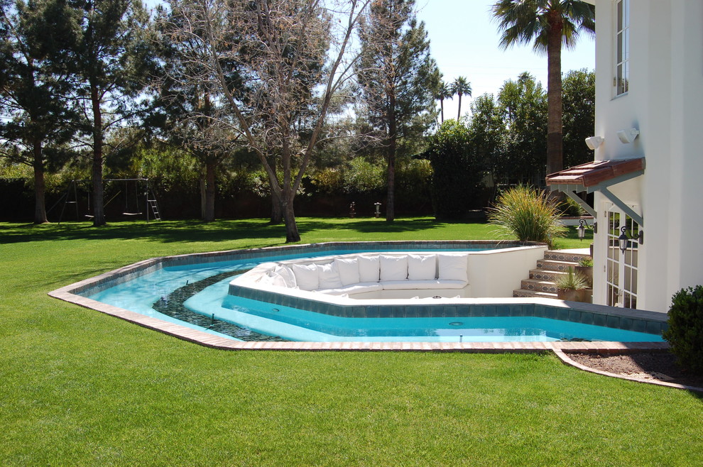 Tuscan brick and custom-shaped pool photo in Phoenix