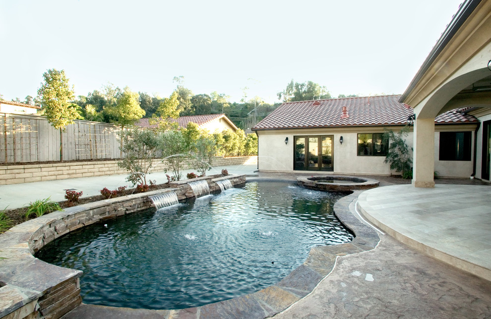 Diseño de piscinas y jacuzzis alargados mediterráneos extra grandes a medida en patio trasero con adoquines de piedra natural