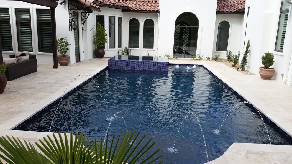 Foto di un'ampia piscina monocorsia mediterranea rettangolare dietro casa con una vasca idromassaggio e cemento stampato
