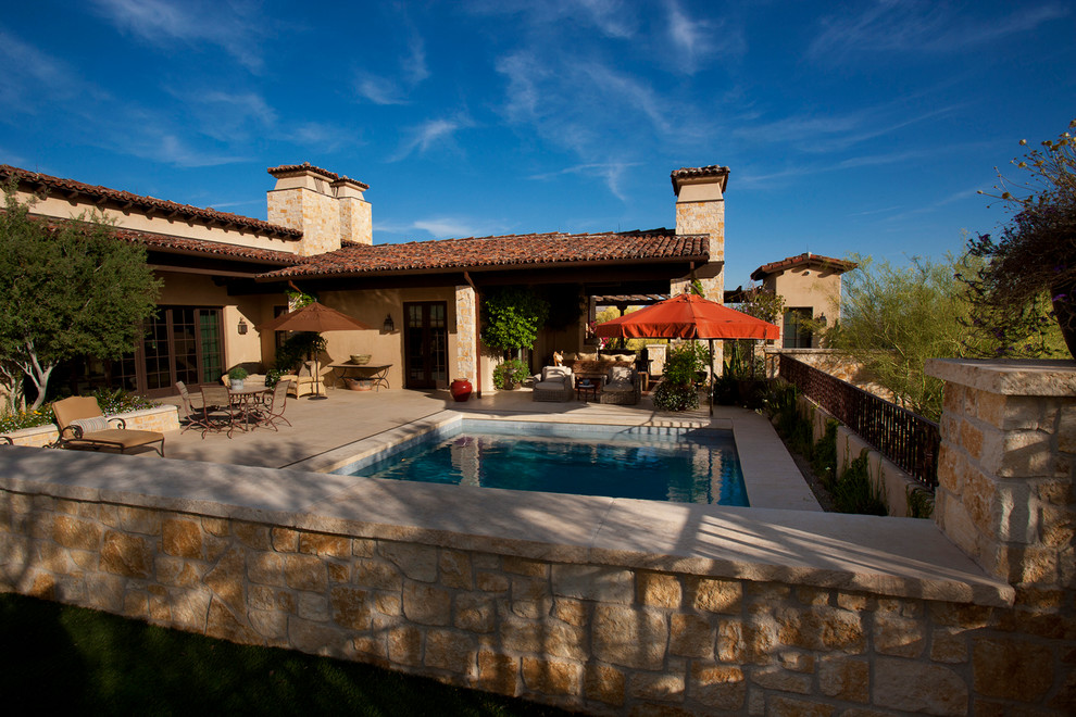 Foto di una piscina mediterranea rettangolare di medie dimensioni e dietro casa con piastrelle e una vasca idromassaggio