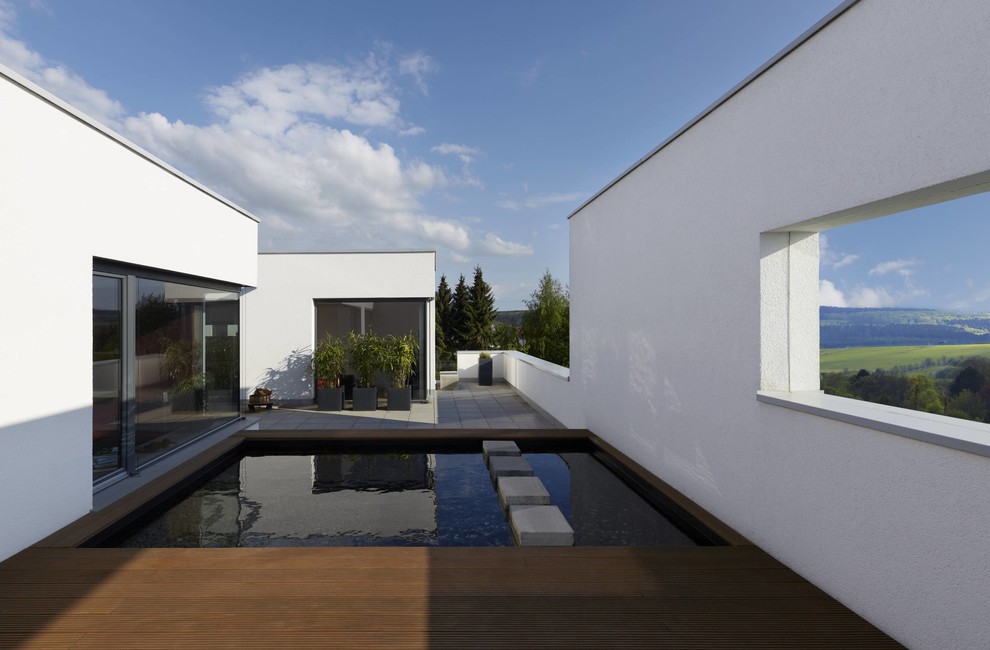 Diseño de piscina alargada contemporánea pequeña a medida en patio trasero con entablado