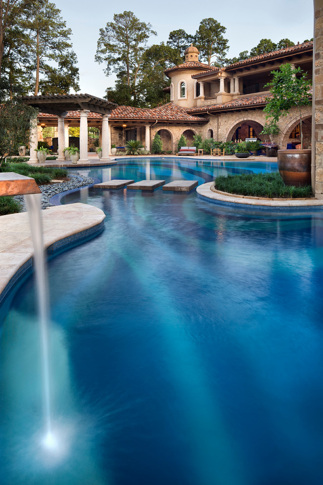 На фото: огромный бассейн произвольной формы на заднем дворе в средиземноморском стиле с