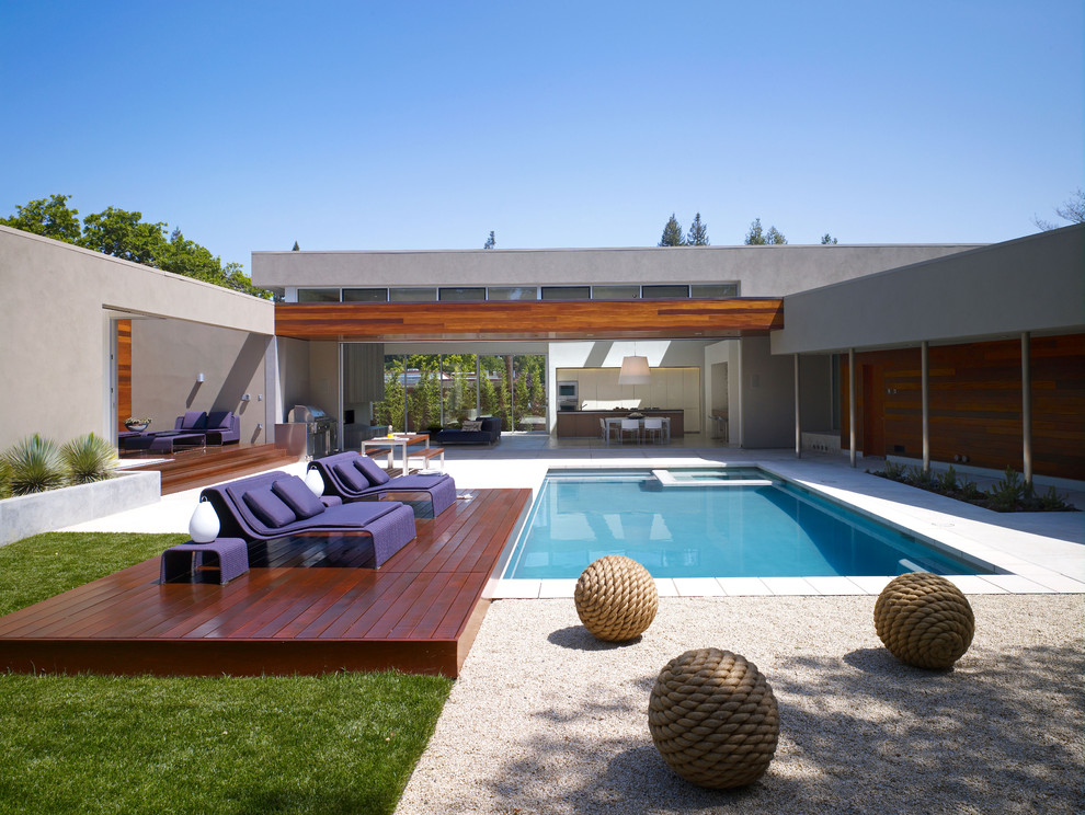 Imagen de piscina actual rectangular en patio con adoquines de hormigón