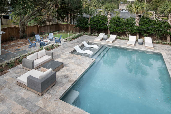 Ejemplo de piscina con fuente natural costera de tamaño medio en forma de L en patio trasero con adoquines de piedra natural