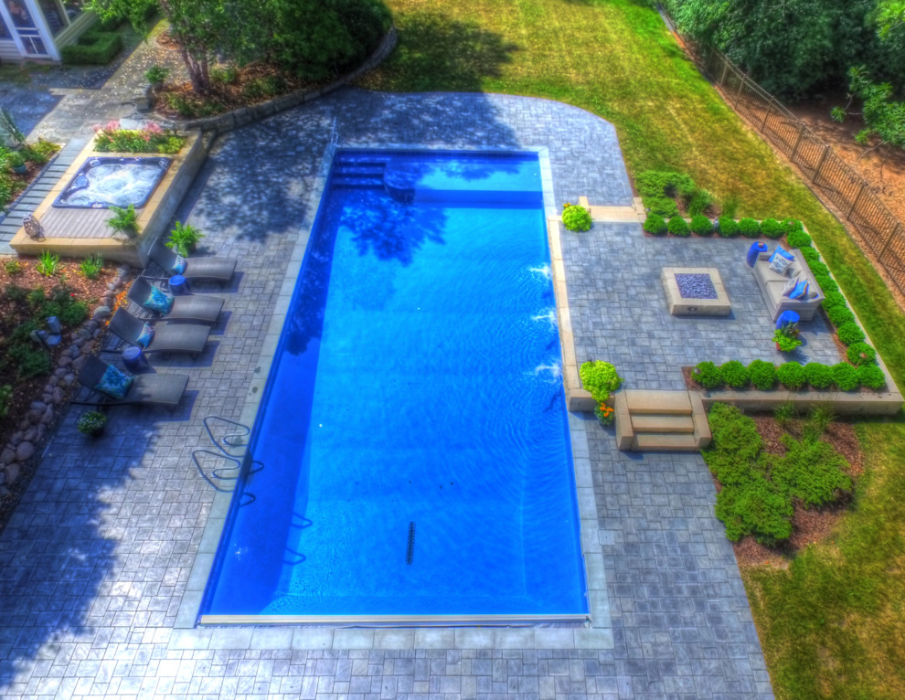 Foto di un'ampia piscina naturale chic rettangolare dietro casa con una vasca idromassaggio e pavimentazioni in cemento