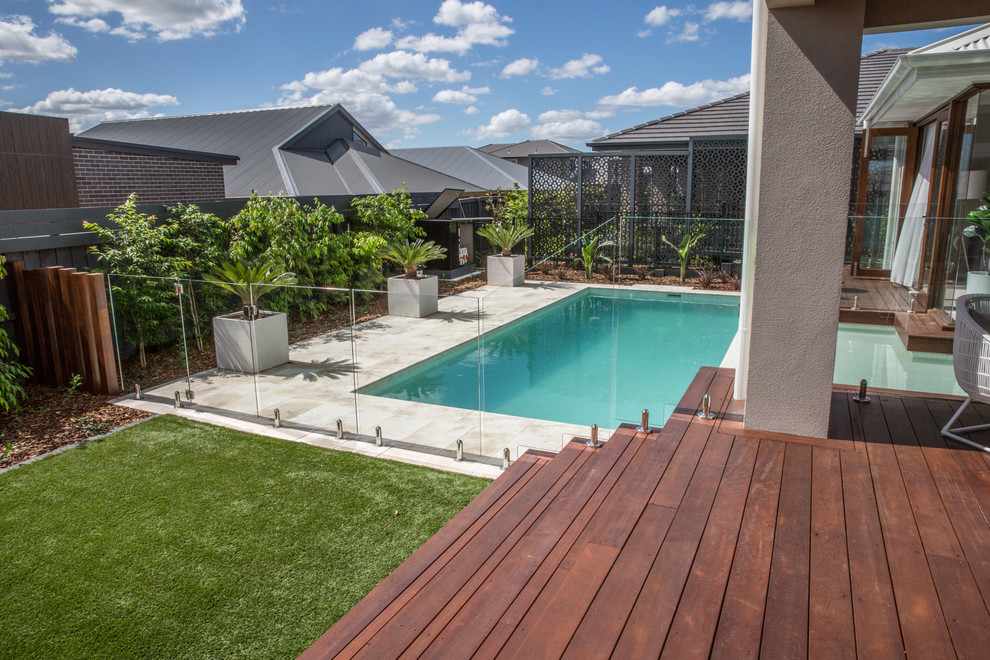 Diseño de piscina alargada actual de tamaño medio rectangular en patio trasero con adoquines de piedra natural