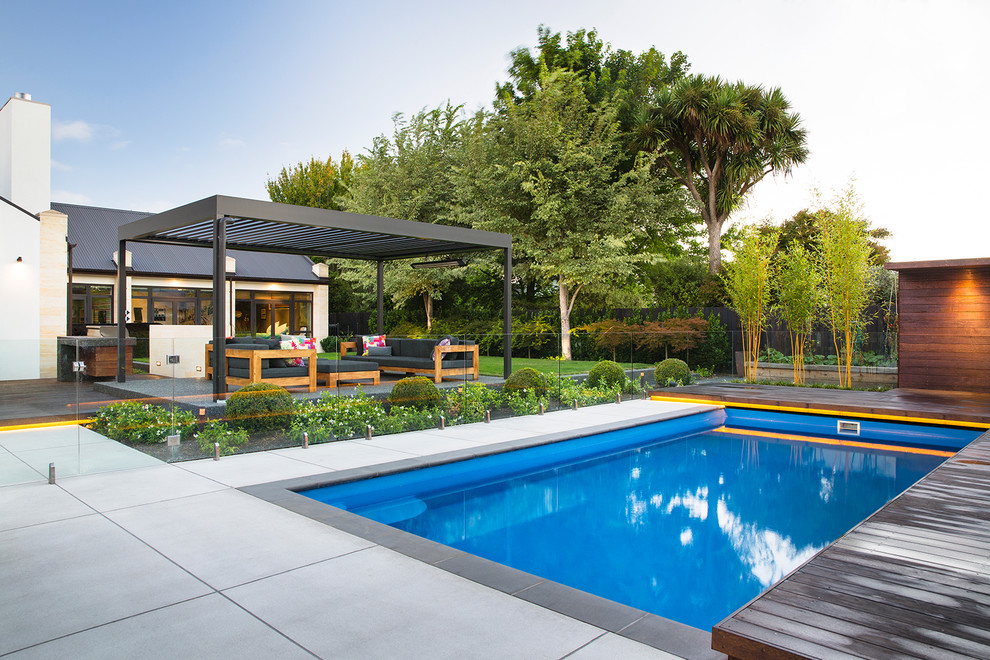 Ejemplo de piscina alargada actual rectangular en patio trasero con losas de hormigón