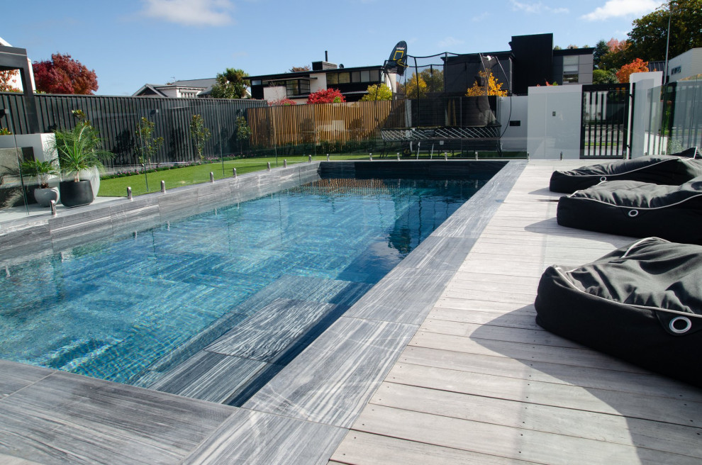 Immagine di una grande piscina monocorsia minimalista rettangolare davanti casa con paesaggistica bordo piscina e piastrelle