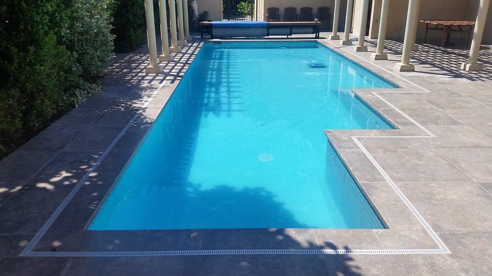Foto de piscina actual grande rectangular en patio trasero con suelo de baldosas