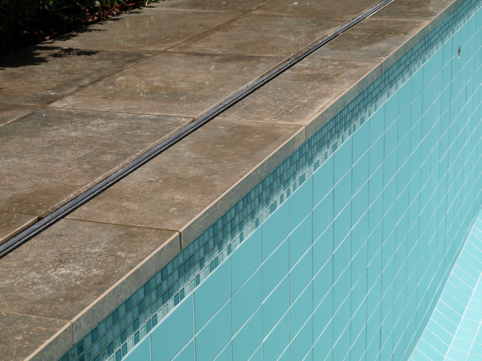 Modelo de piscina contemporánea grande rectangular en patio trasero con suelo de baldosas