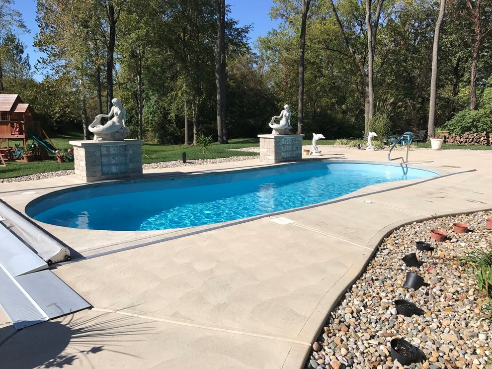 Ejemplo de piscina con fuente alargada clásica renovada de tamaño medio redondeada en patio trasero con suelo de hormigón estampado