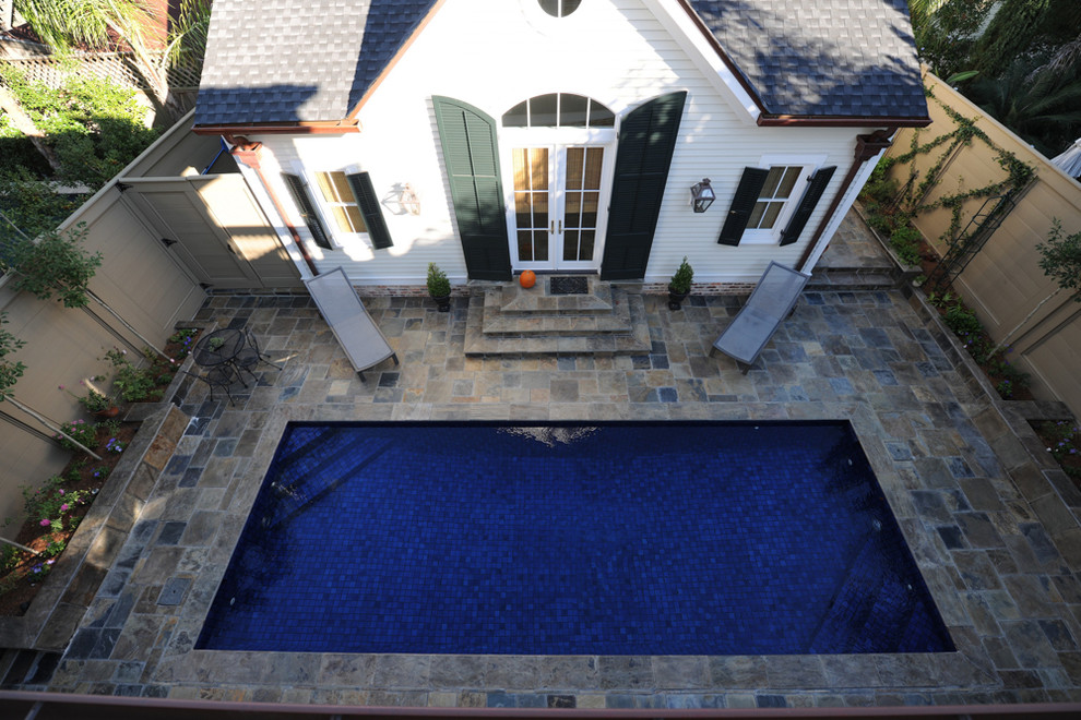 Modelo de piscina alargada tradicional de tamaño medio rectangular en patio trasero con adoquines de piedra natural