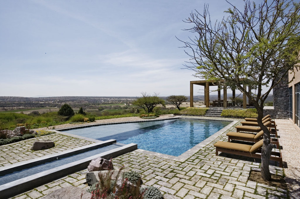 Example of a mid-sized tuscan backyard brick and custom-shaped pool design in New York