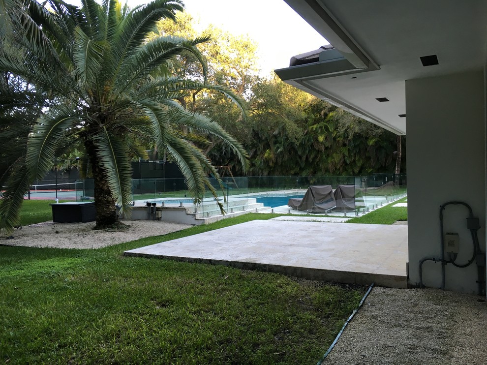 Modelo de piscinas y jacuzzis costeros grandes rectangulares en patio trasero con losas de hormigón