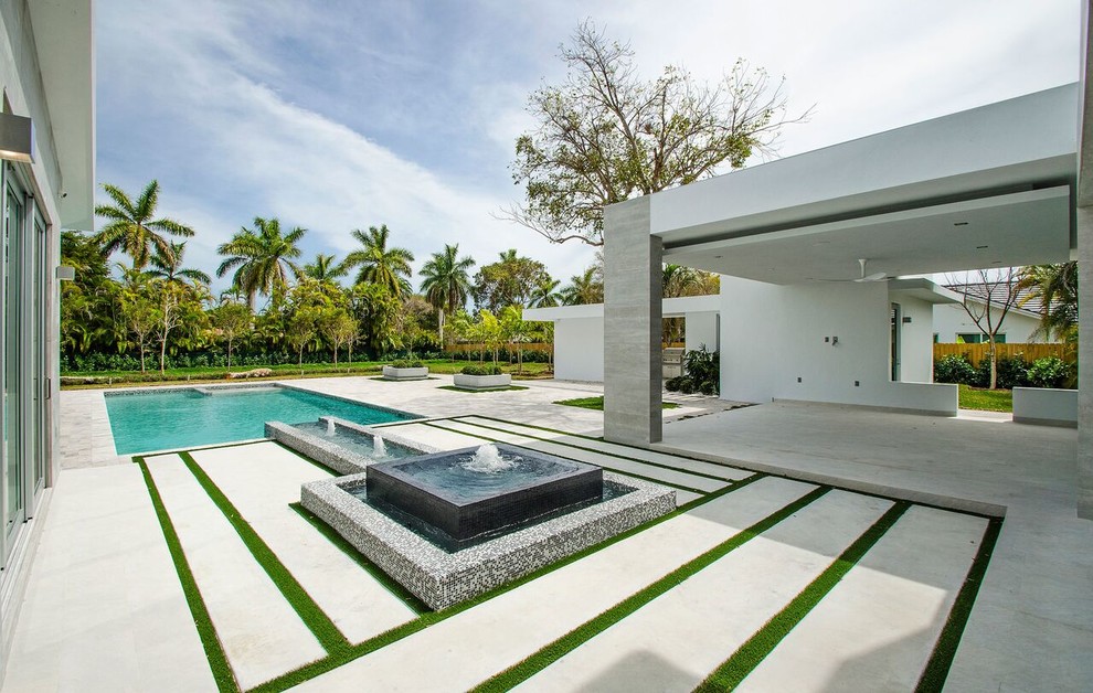 Diseño de piscina con fuente moderna grande rectangular en patio trasero