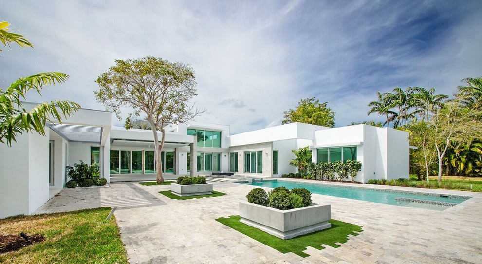 Ejemplo de piscina con fuente alargada minimalista grande rectangular en patio trasero con adoquines de ladrillo