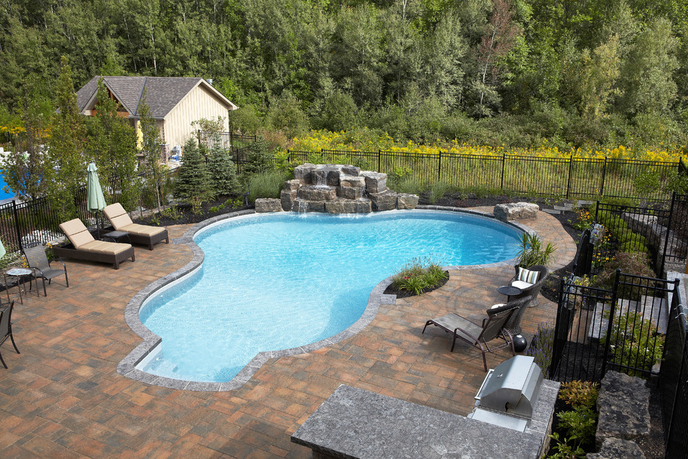 Foto di una grande piscina naturale contemporanea personalizzata dietro casa con fontane e pavimentazioni in pietra naturale