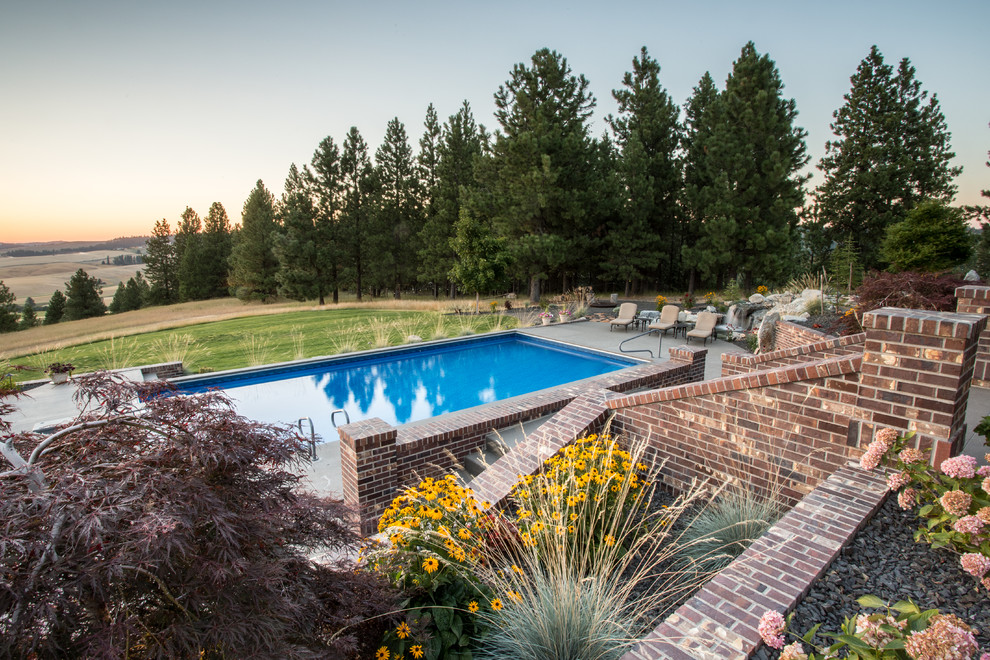 Foto de piscinas y jacuzzis tradicionales grandes rectangulares en patio trasero con losas de hormigón