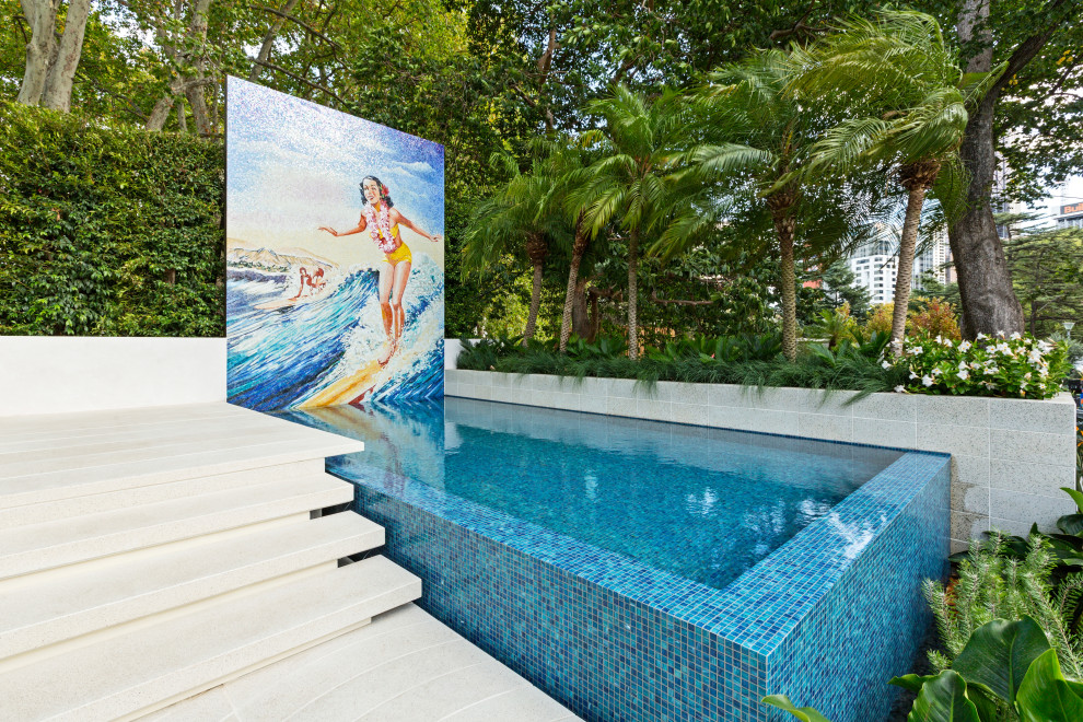 Esempio di una piscina a sfioro infinito tropicale rettangolare di medie dimensioni e dietro casa con piastrelle
