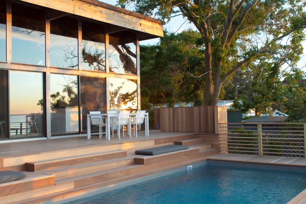 Ejemplo de piscinas y jacuzzis alargados retro grandes rectangulares en patio trasero con entablado