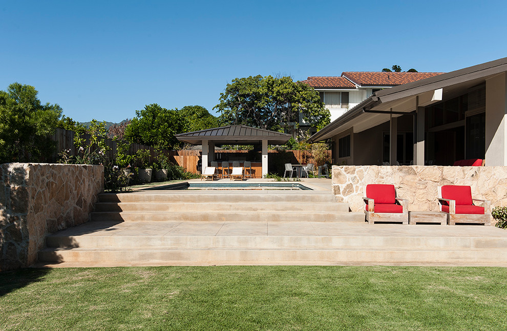 Foto de piscina elevada retro grande rectangular en patio trasero con adoquines de piedra natural