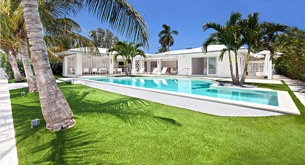 Example of a mid-sized mid-century modern backyard stone and custom-shaped lap pool design in Miami