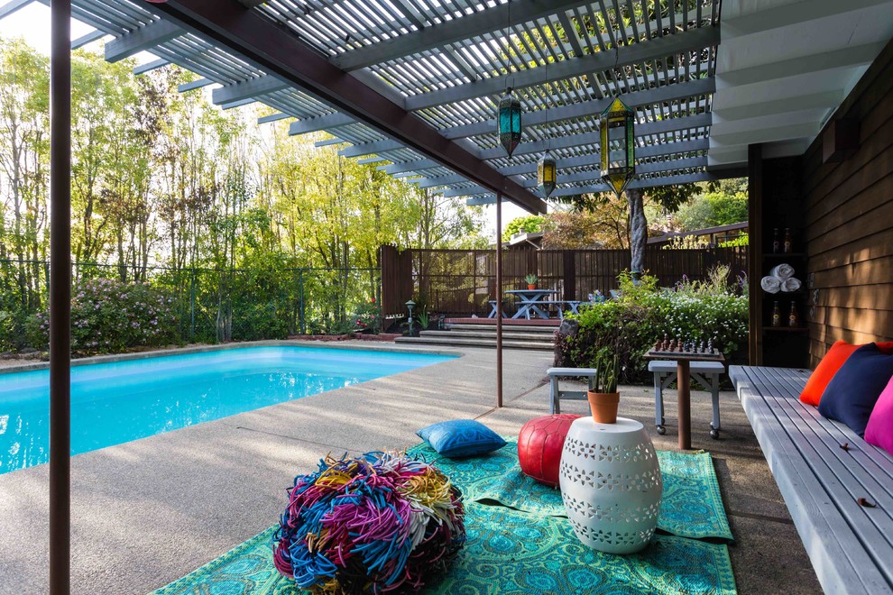 Ejemplo de piscina alargada retro grande rectangular en patio trasero con suelo de hormigón estampado
