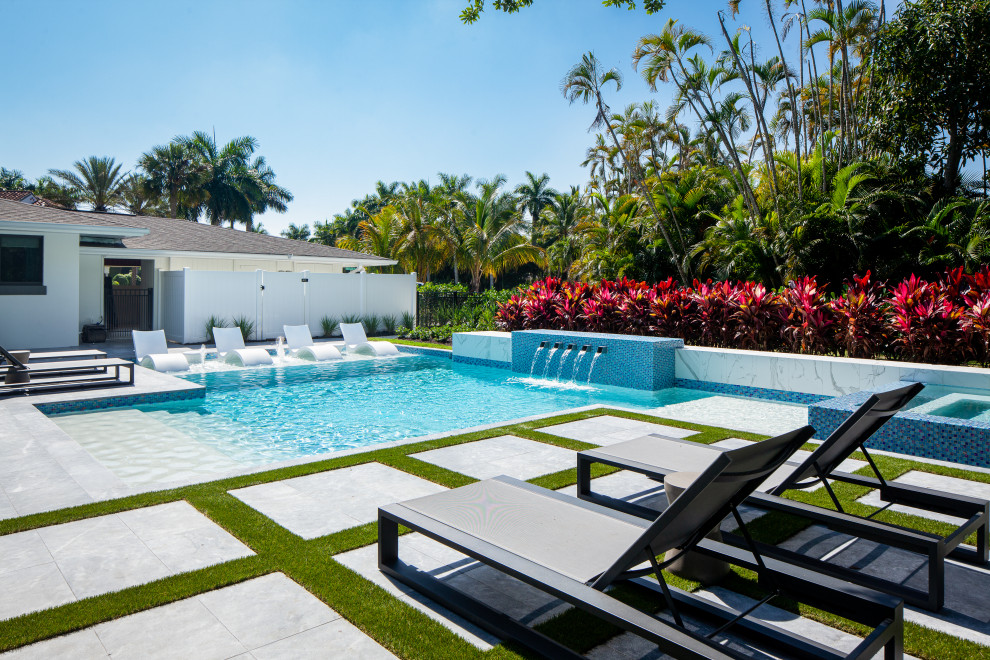 Großes Mid-Century Sportbecken hinter dem Haus in individueller Form mit Wasserspiel und Natursteinplatten in Miami