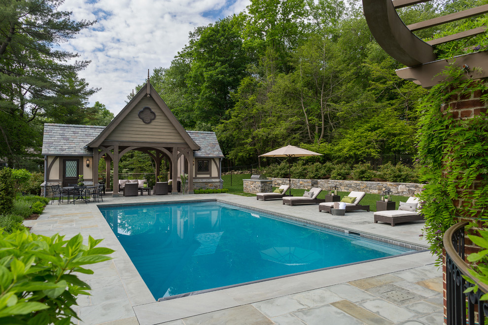 Diseño de piscina alargada tradicional rectangular en patio trasero con adoquines de piedra natural
