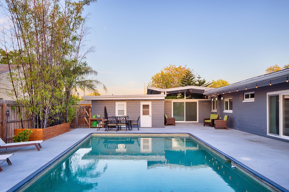 Esempio di una piscina monocorsia minimalista rettangolare dietro casa con lastre di cemento
