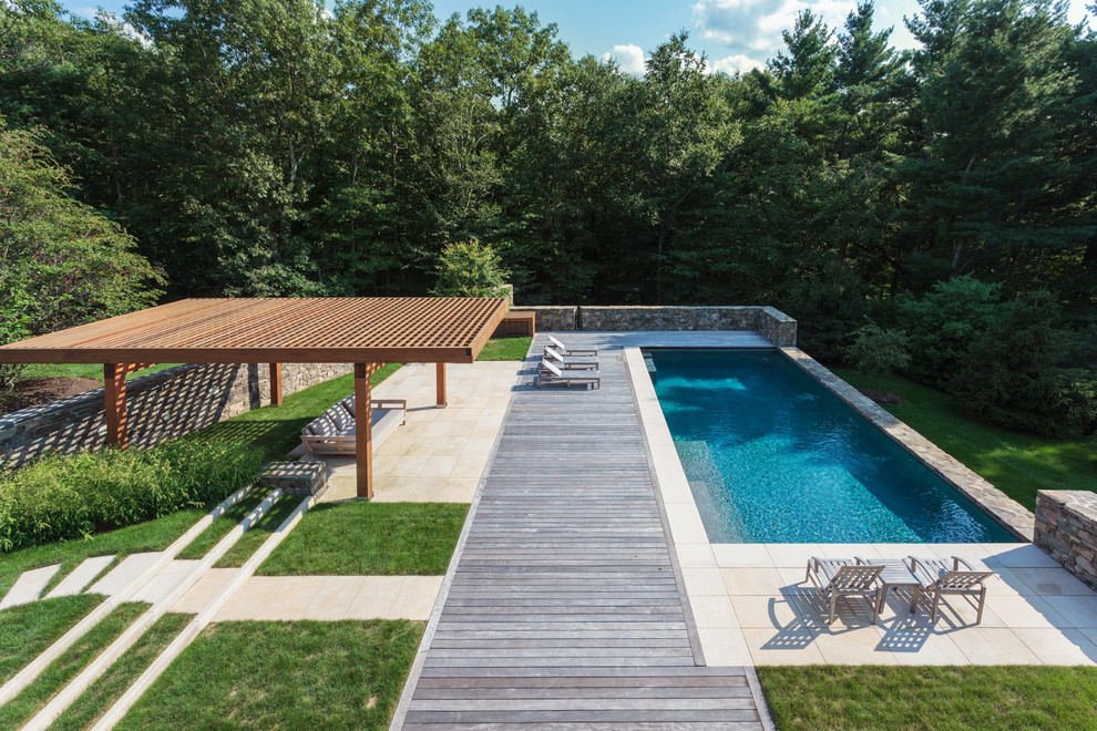 Réalisation d'une grande piscine tradition rectangle avec une terrasse en bois.