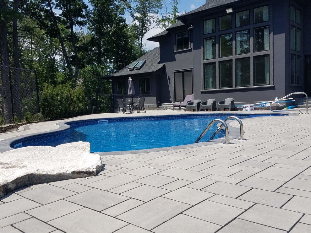 Foto de piscina natural grande a medida en patio trasero con adoquines de hormigón